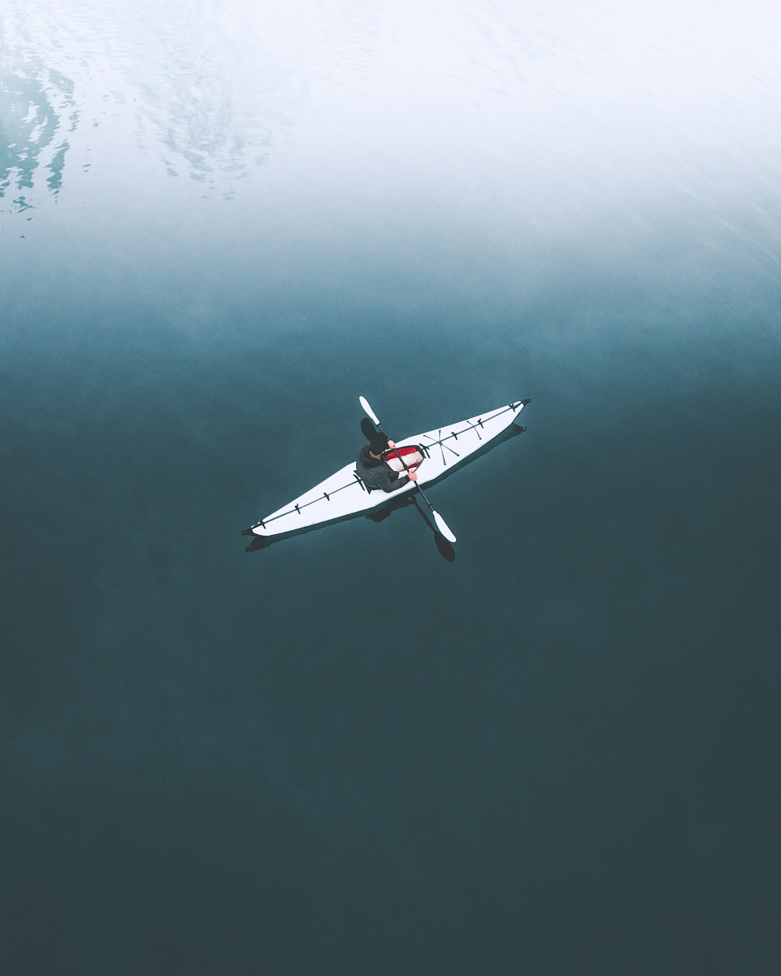 aerial view of a paddler in a white kayak on still dark water - Rivara Kayak - paddle sports gear for dealers